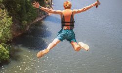 A man jumping off a cliff into a river