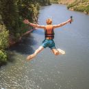 A man jumping off a cliff into a river